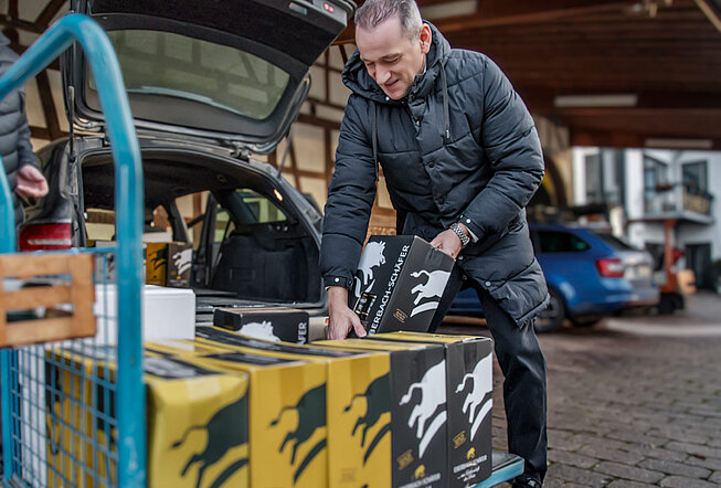 Herr Schäfer lädt einem Kunden Wein ins Auto