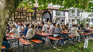 Menschen auf Bierbänken beim Weinfest