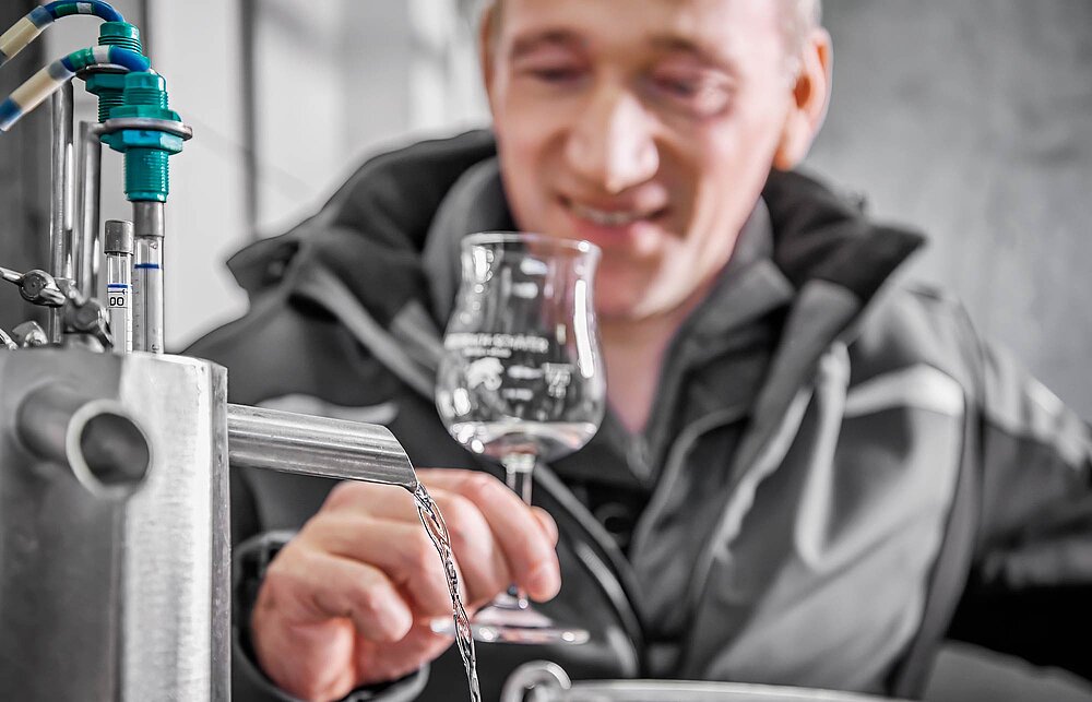 Herr Schäfer mit Probenglas vor dem Auslauf